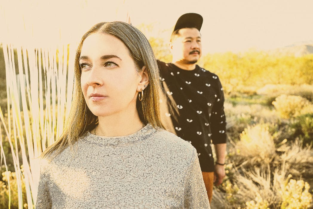 Photo of LA band GEMZ, with the female and male duo standing in a field during sunset.