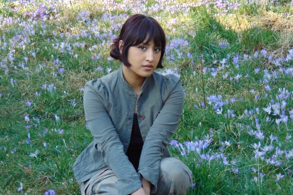 Press shot of London pop-artist Aniwa showing the artist sitting in a blooming meadow